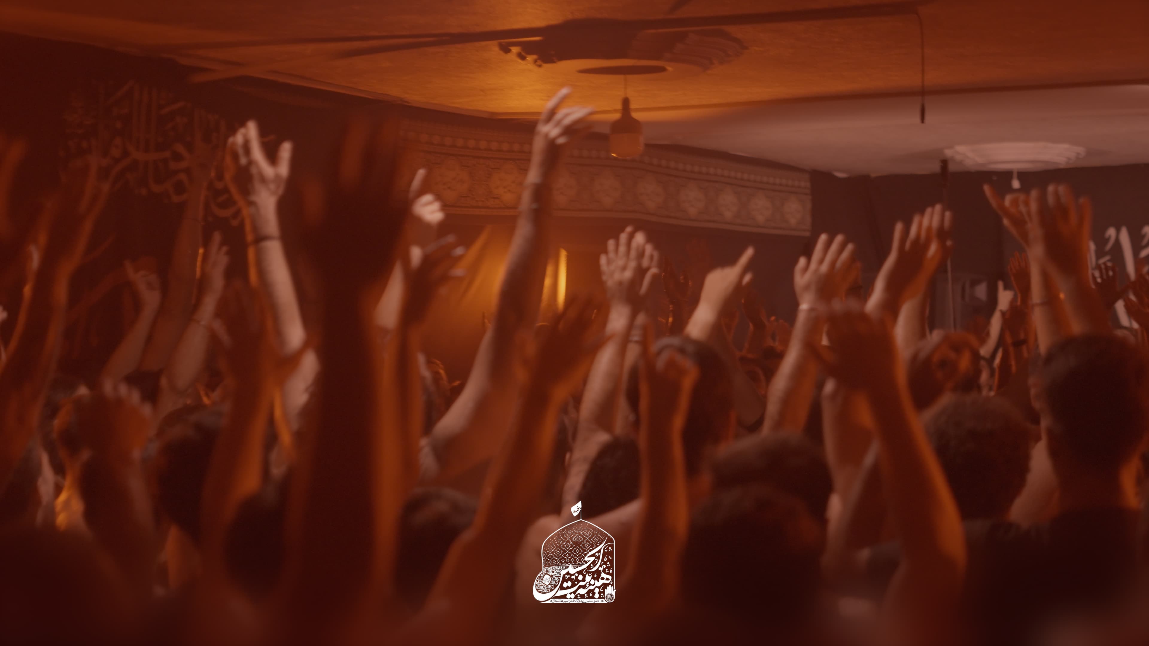 A sea of raised hands in warm amber light during a latmiya